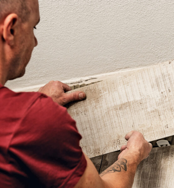 Eine graue Platte wird von einem Richli Mitarbeiter mit Tattoo verlegt – Reto